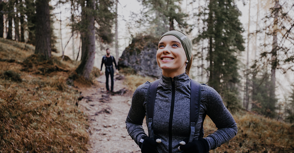 A woman hiking in the mountains with her partner in the background